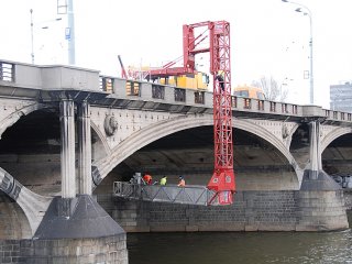 práce pod mostem nad hladinou řeky Vltavy